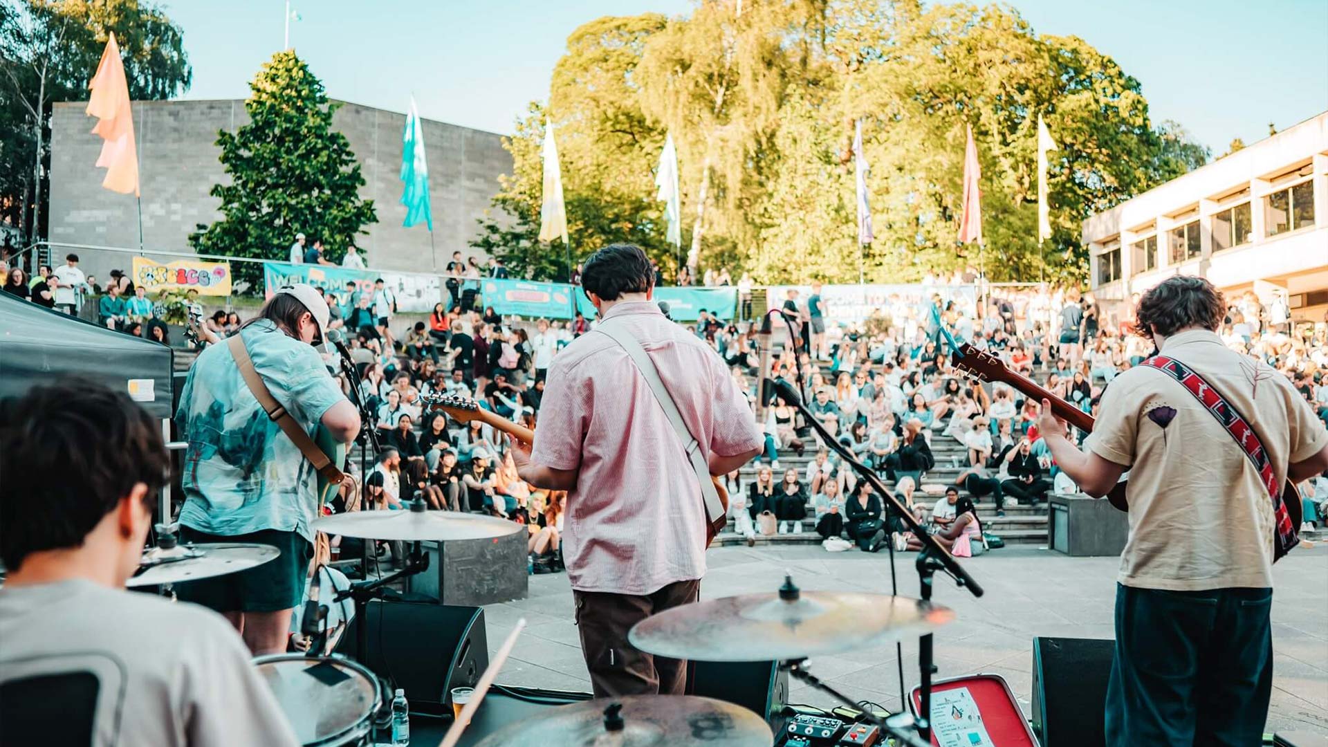 A photograph of a band playing on campus on a sunny day