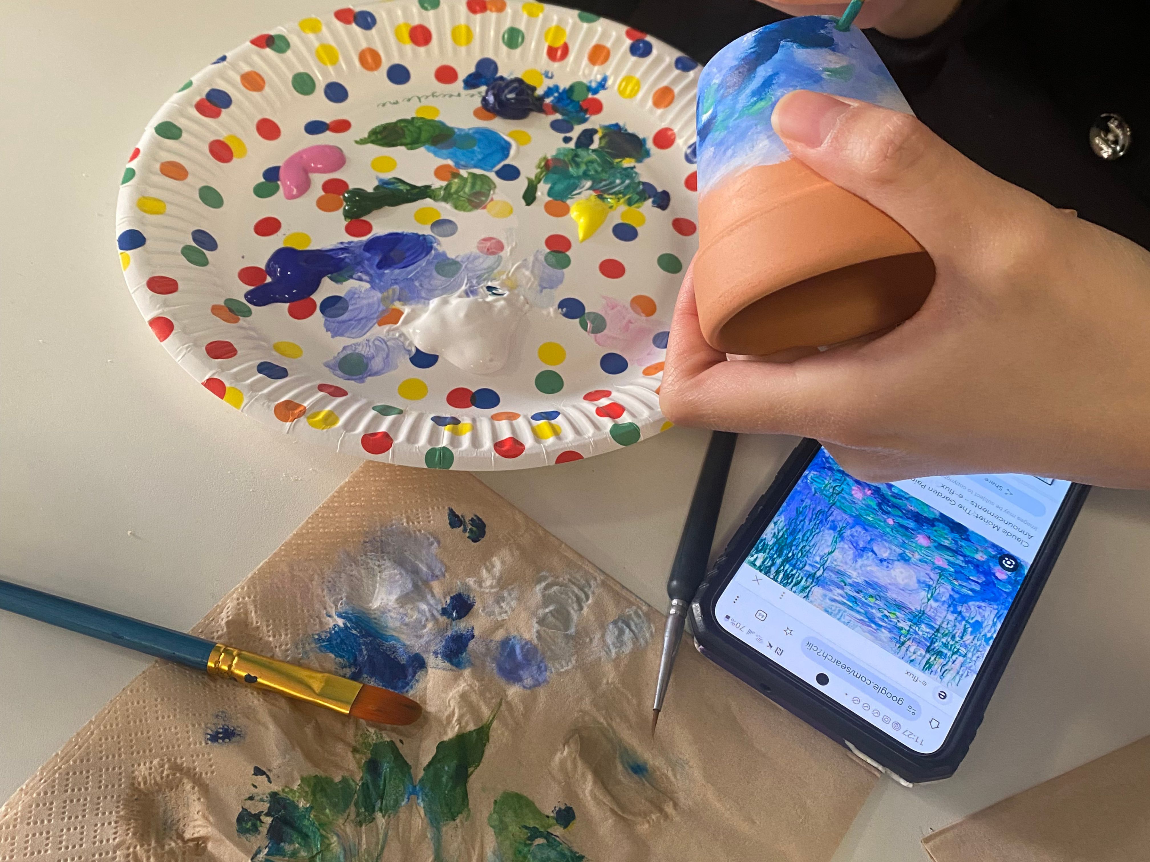 A photograph of a someone painting a plant pot