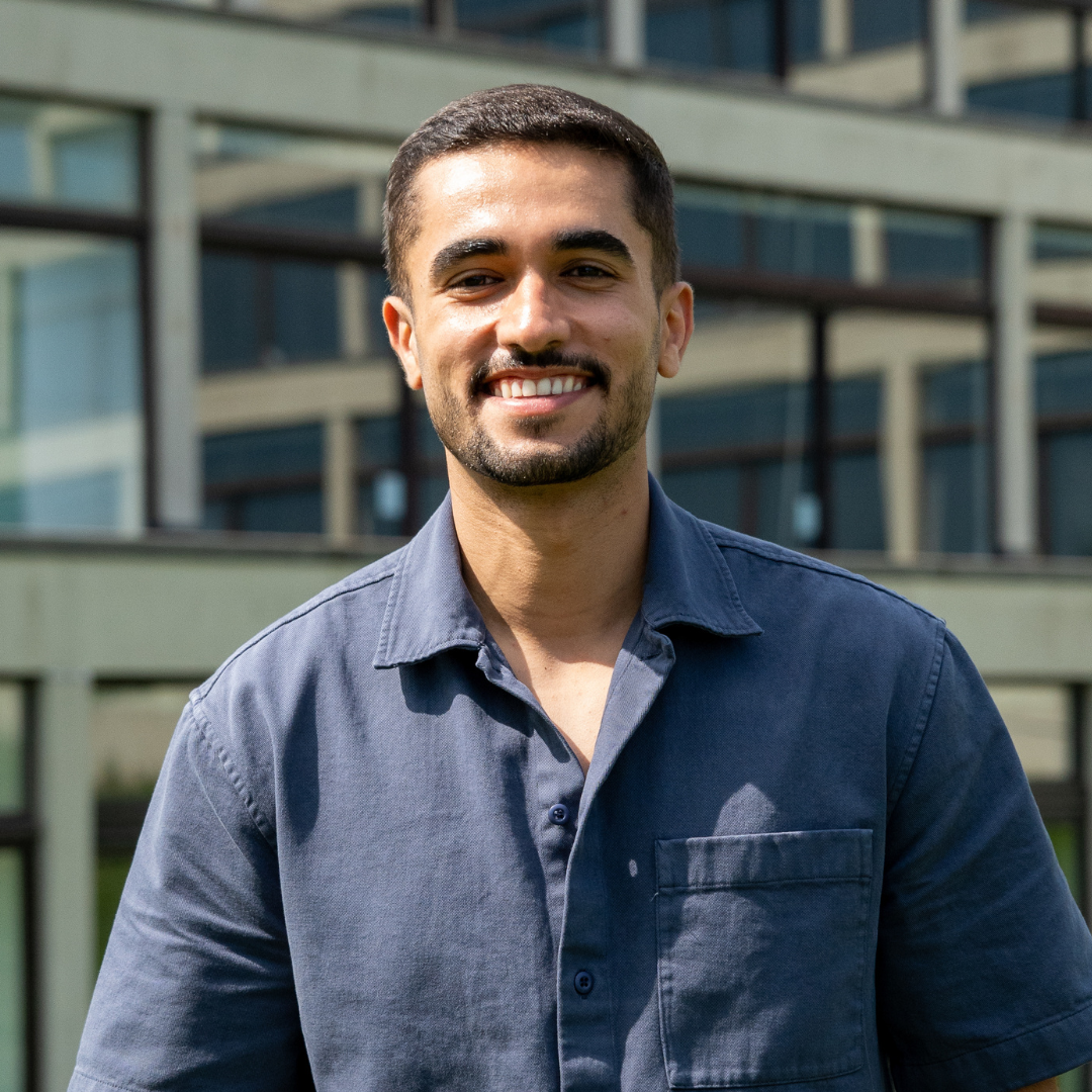 Amjad smiling against a backdrop of trees