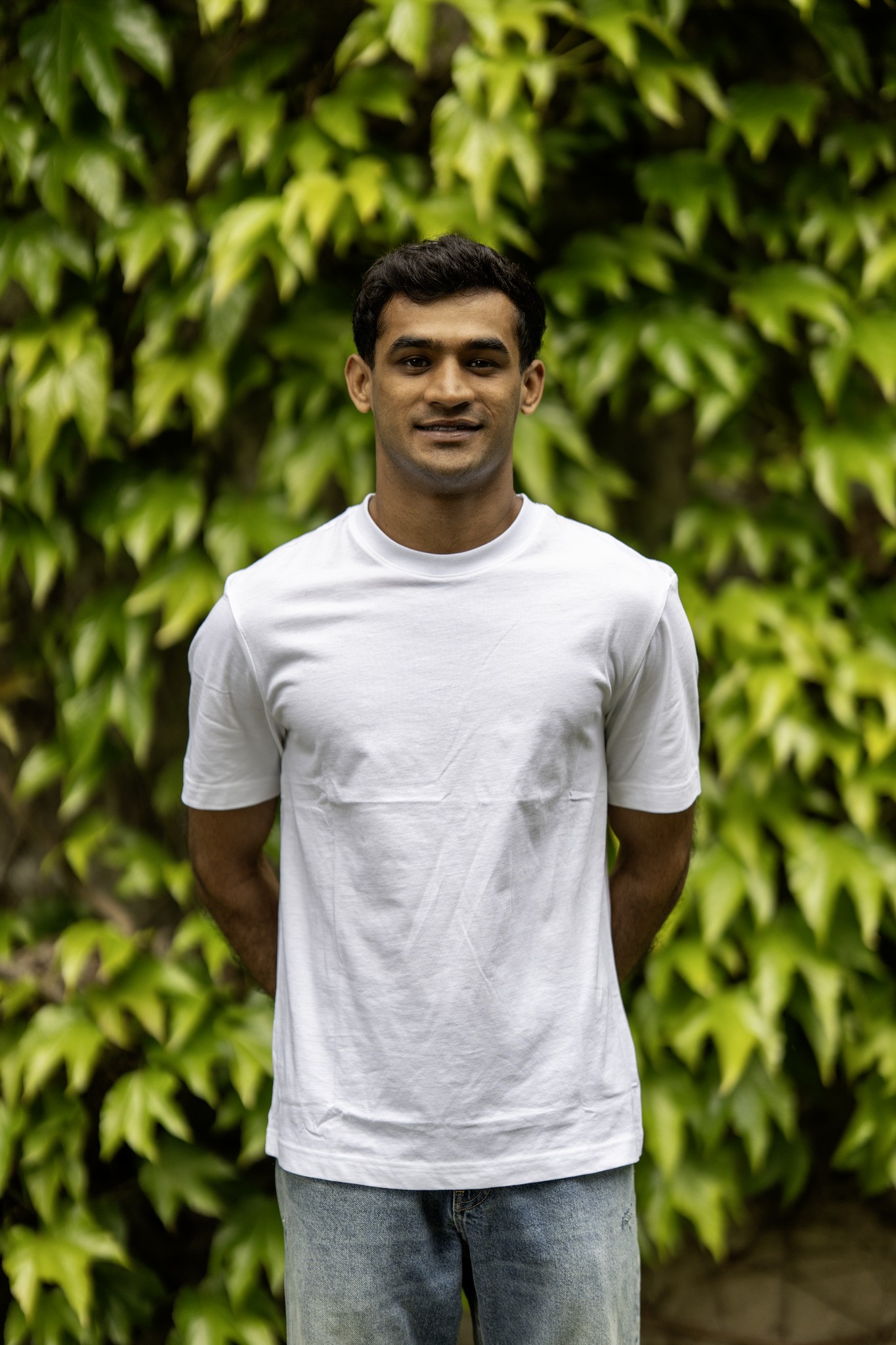 Amin smiling against a backdrop of trees